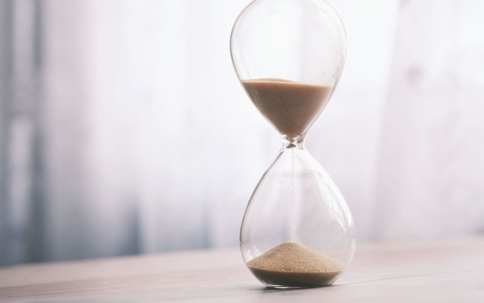 An hourglass on a table, sand running from the upper bulb