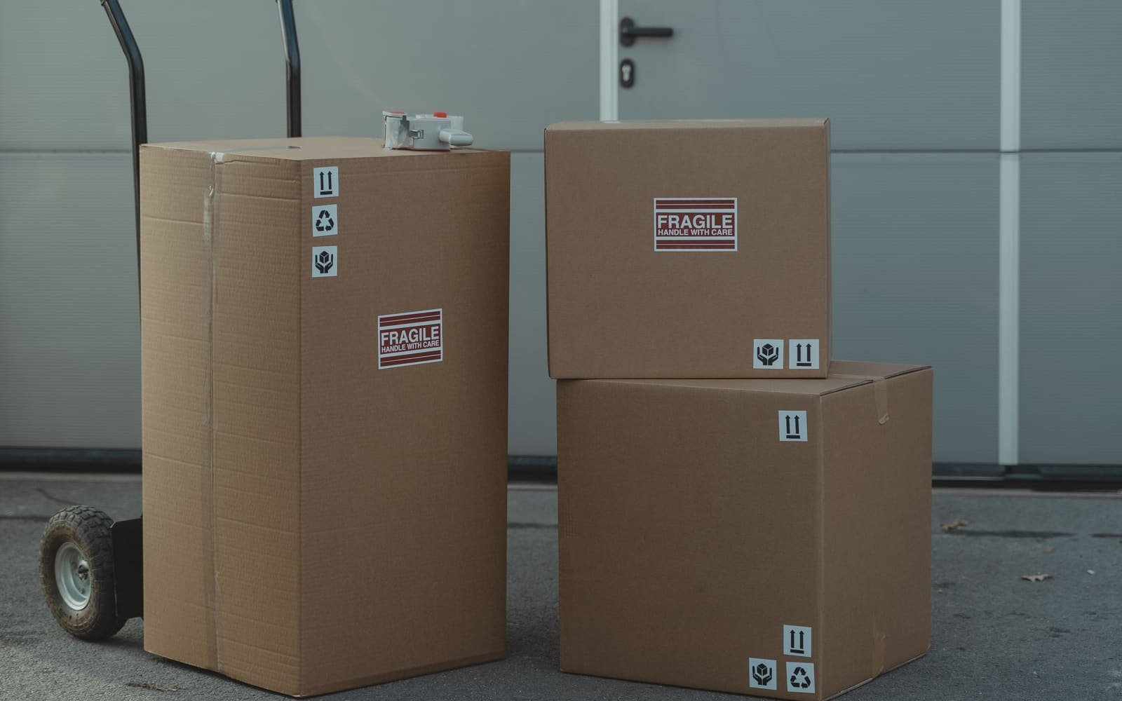 Sealed shipping cartons and a hand truck at a loading door